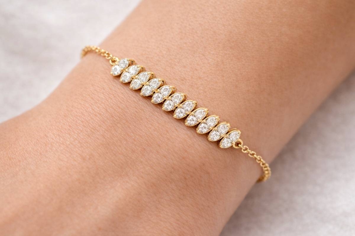 Gold bracelet with diamonds on a wrist against a neutral background