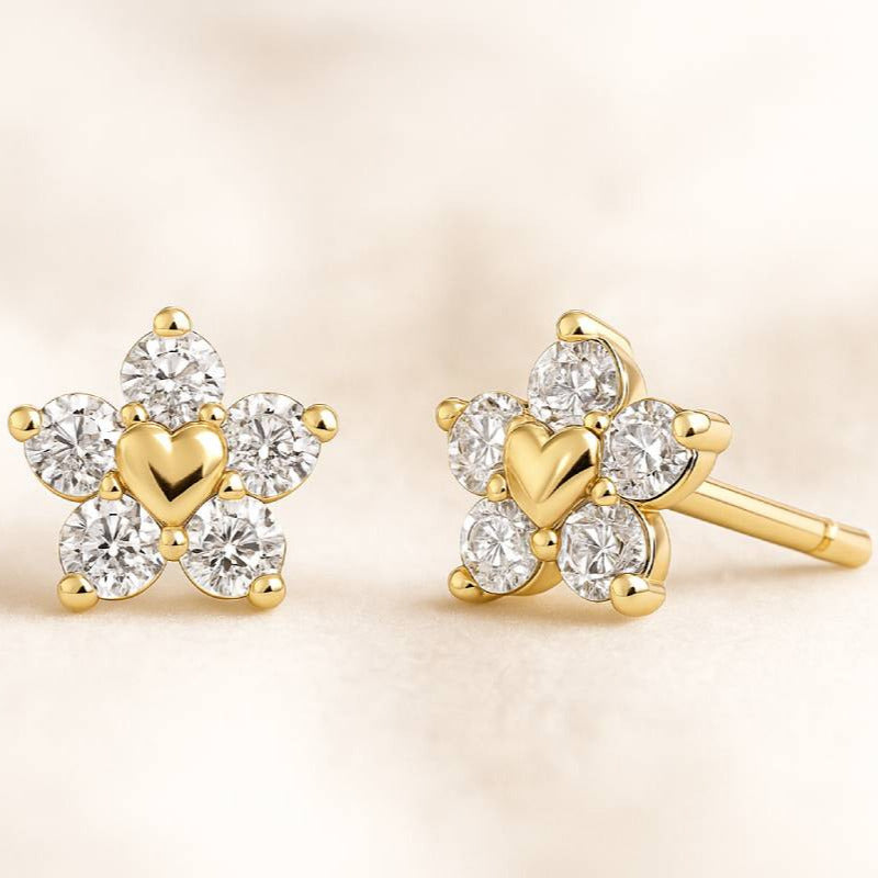 Gold earrings with heart and diamond design on a beige background