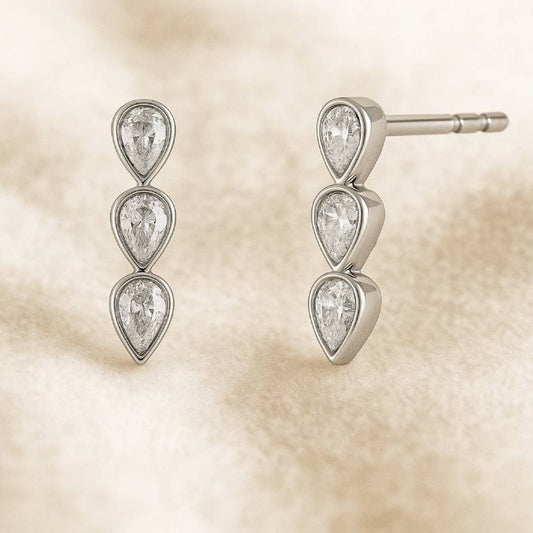Pair of earrings with teardrop-shaped gemstones on a beige background