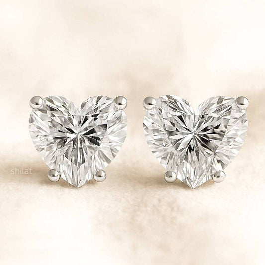 Heart-shaped diamond earrings on a beige background