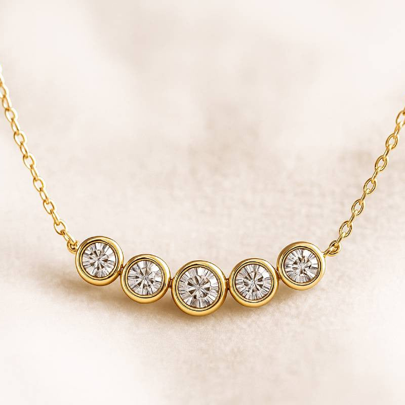 Gold necklace with five diamond stones on a beige background