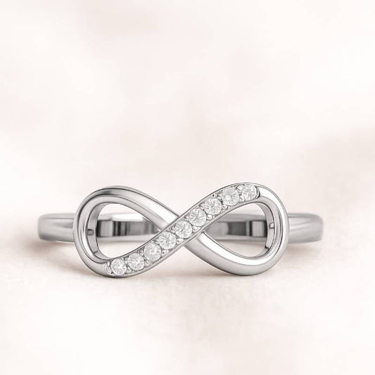 infinity ring with embedded diamonds on a light pink background