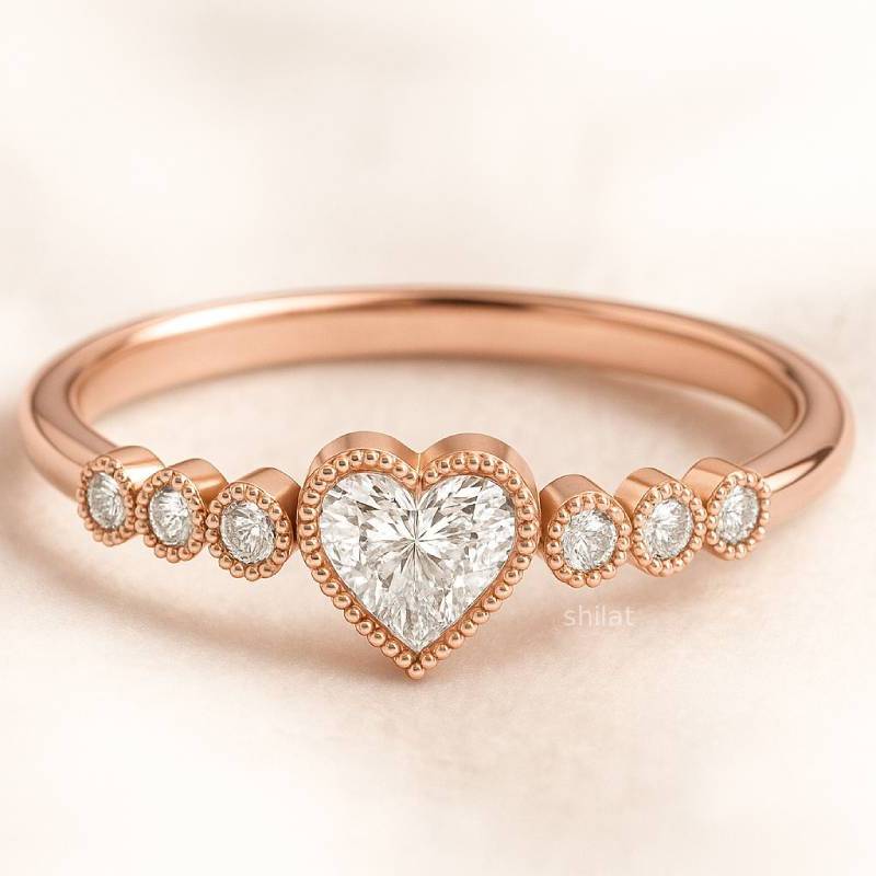Rose gold ring with a heart-shaped diamond and smaller diamonds on a light background
