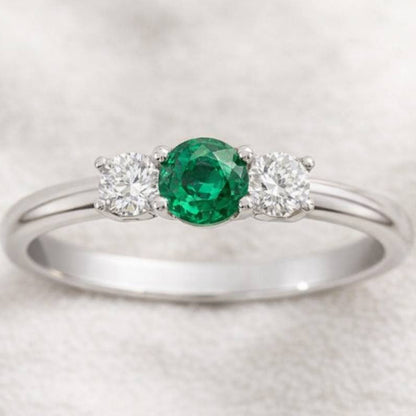  ring with a green gemstone and two smaller diamonds on a light gray background