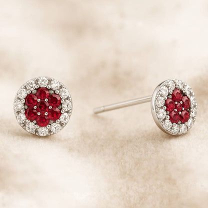 Pair of earrings with red gemstones and diamond-like stones on a beige background