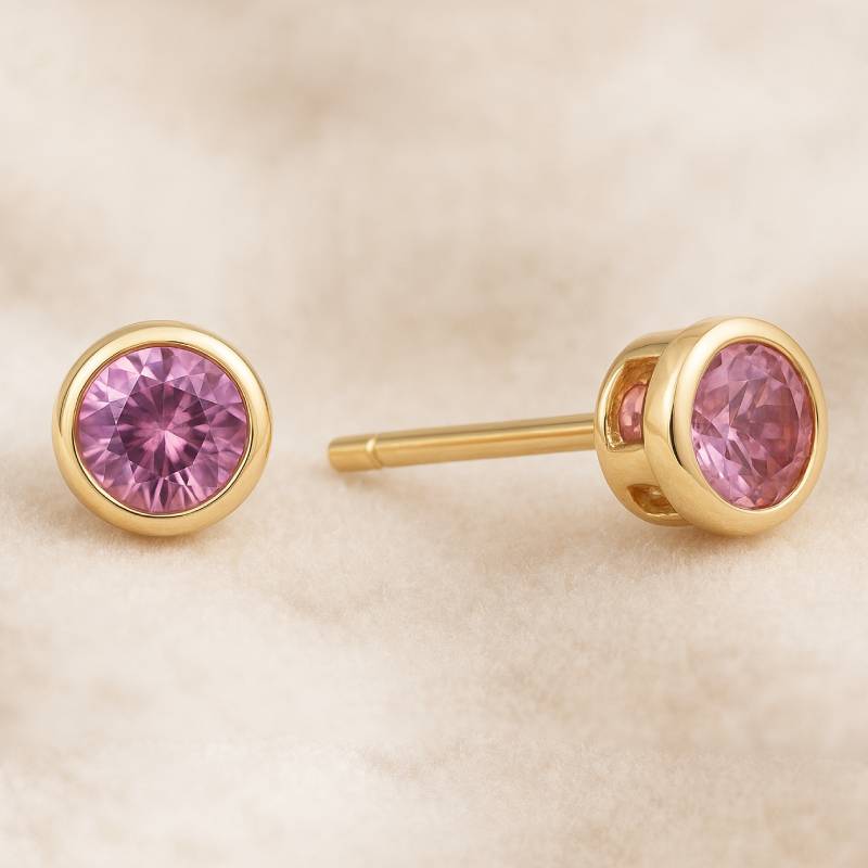 Gold earrings with pink gemstones on a beige background