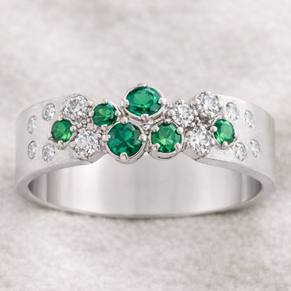 ring with green gemstones on a light gray background