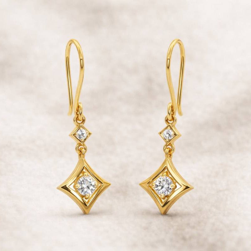 Gold earrings with diamond-like stones on a beige background