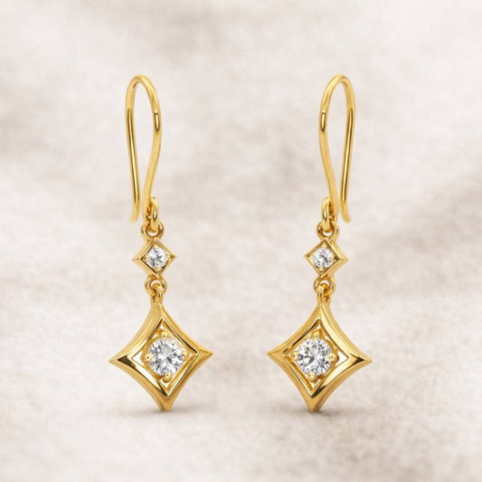Gold earrings with diamond-like stones on a beige background