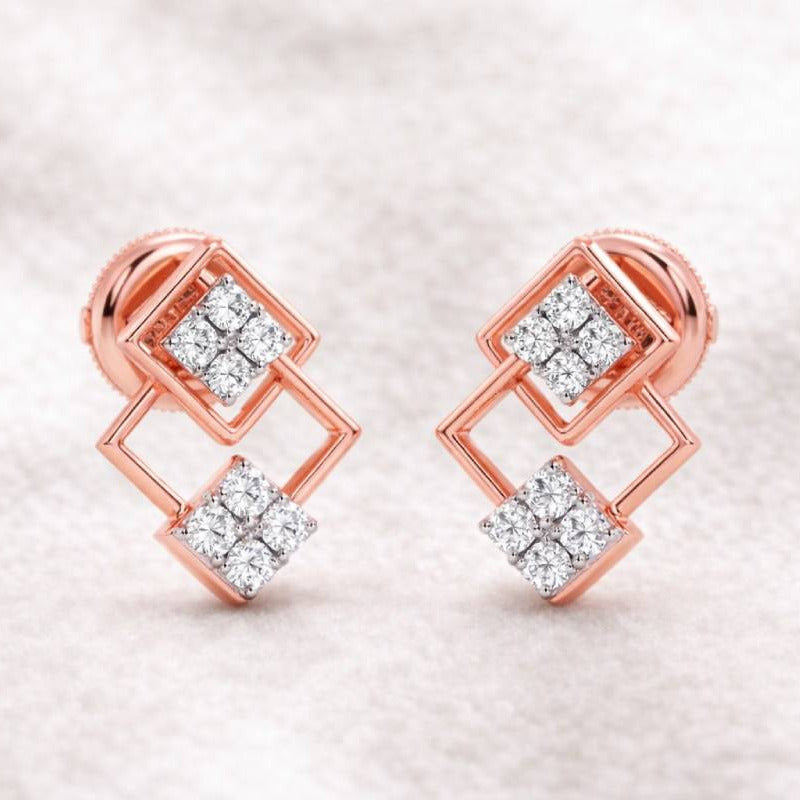 Rose gold earrings with diamond accents on a soft fabric background