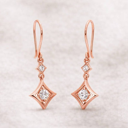 Rose gold earrings with diamond-like stones on a light background