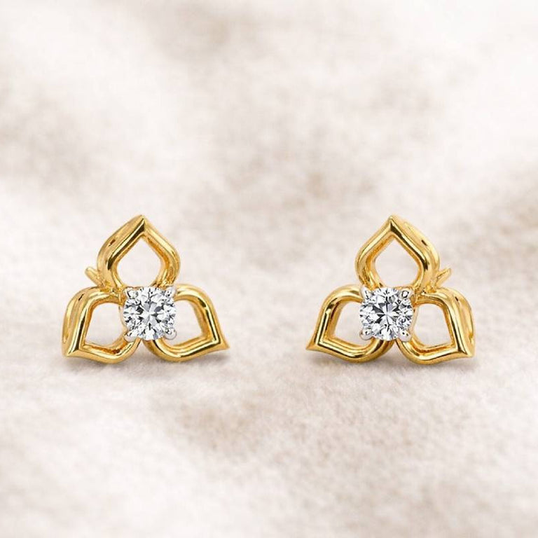 Pair of gold earrings with diamond centers on a soft beige background