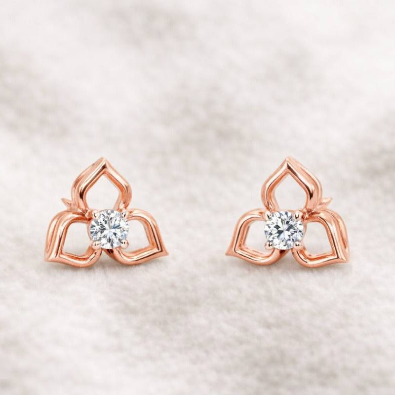 Rose gold earrings with clear gemstones on a soft beige background