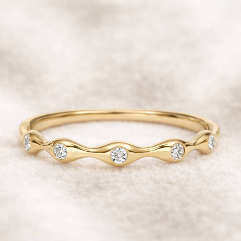 Gold ring with small diamonds on a soft beige background