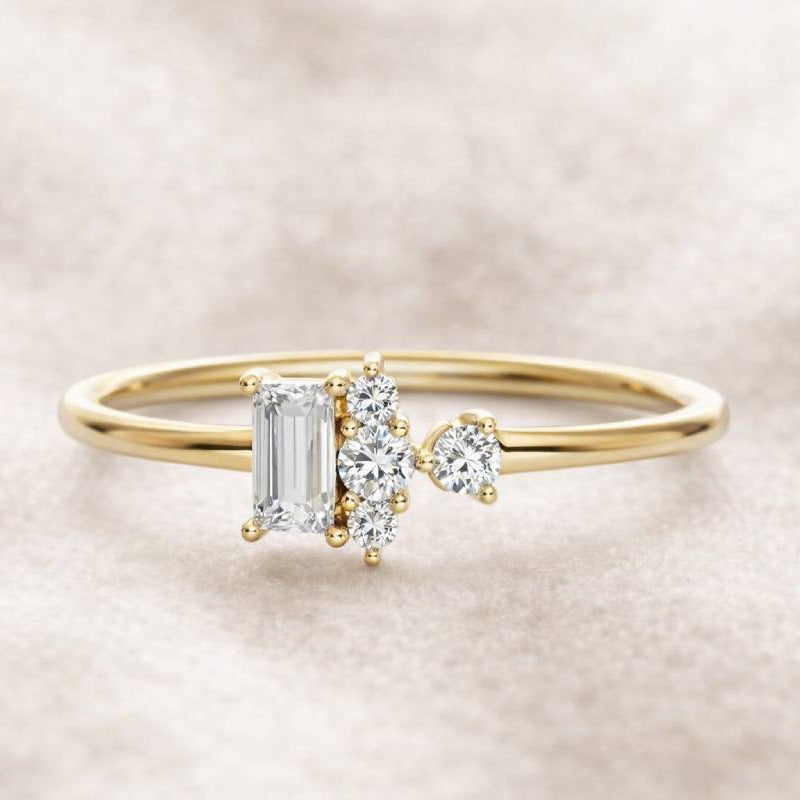 Gold ring with emerald-cut diamond and smaller round diamonds on a beige background