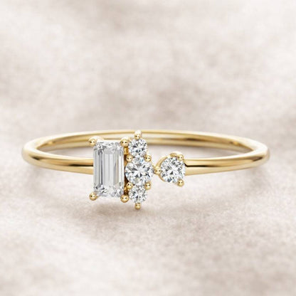 Gold ring with emerald-cut diamond and smaller round diamonds on a beige background