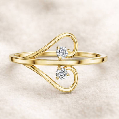 Gold ring with two diamonds on a beige background