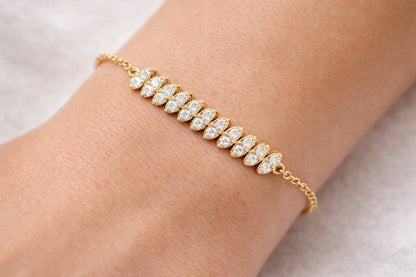 Gold bracelet with diamonds on a wrist against a neutral background