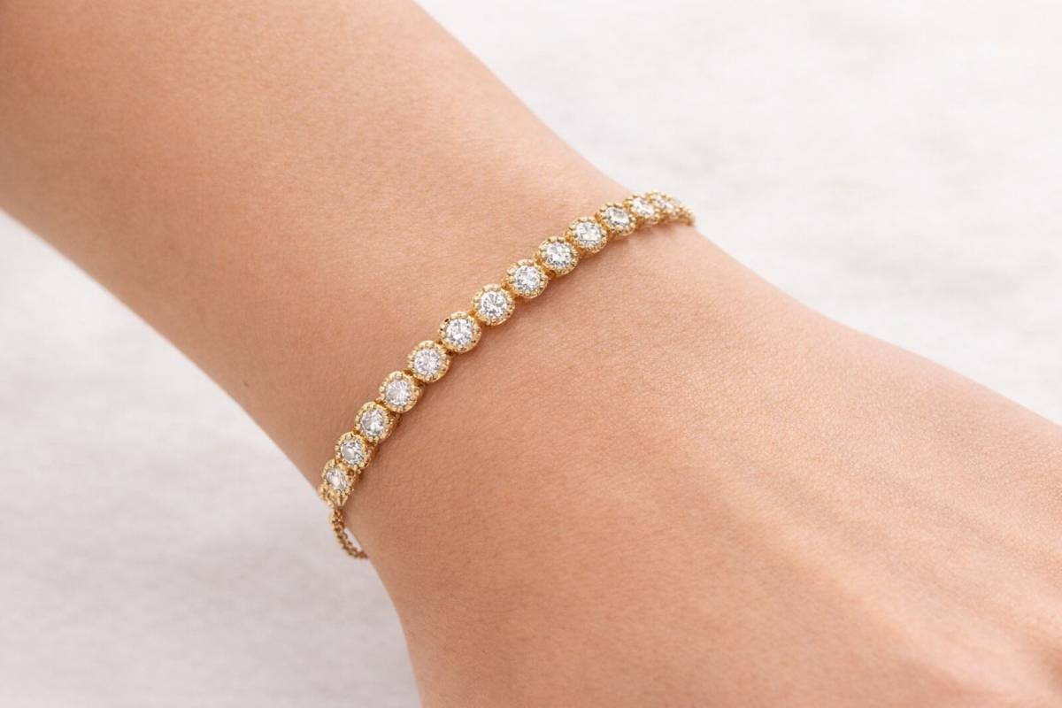 Gold bracelet with diamonds on a wrist against a light background