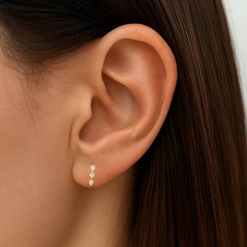 Close-up of an ear wearing a gold earring with small diamonds.