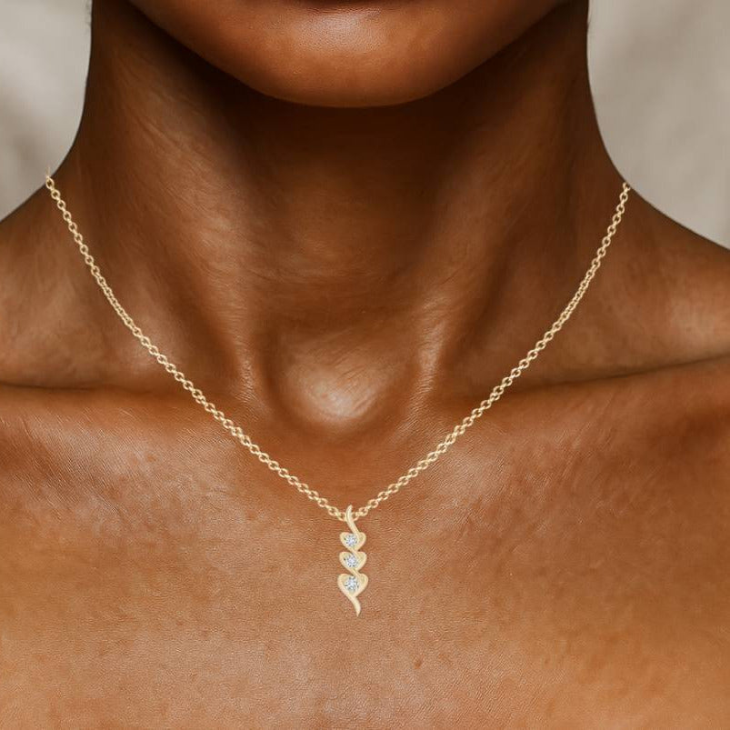 Gold necklace with a heart-shaped pendant on a person's neck