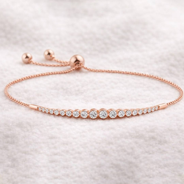 Rose gold bracelet with clear stones on a light gray background