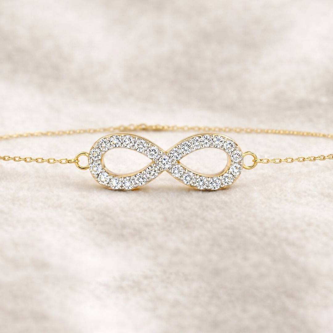 Gold bracelet with an infinity symbol on a beige background