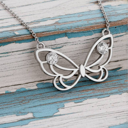 butterfly necklace with gemstones on a wooden surface