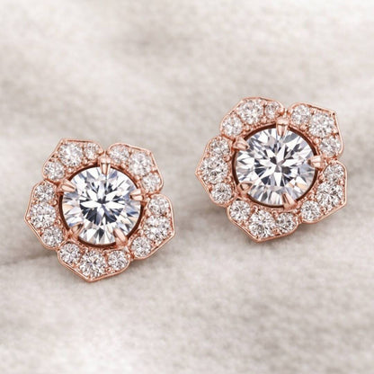 Rose gold earrings with large central gemstones and smaller stones on a light background