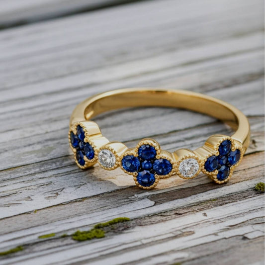 Gold ring with blue gemstones and diamonds on a wooden surface