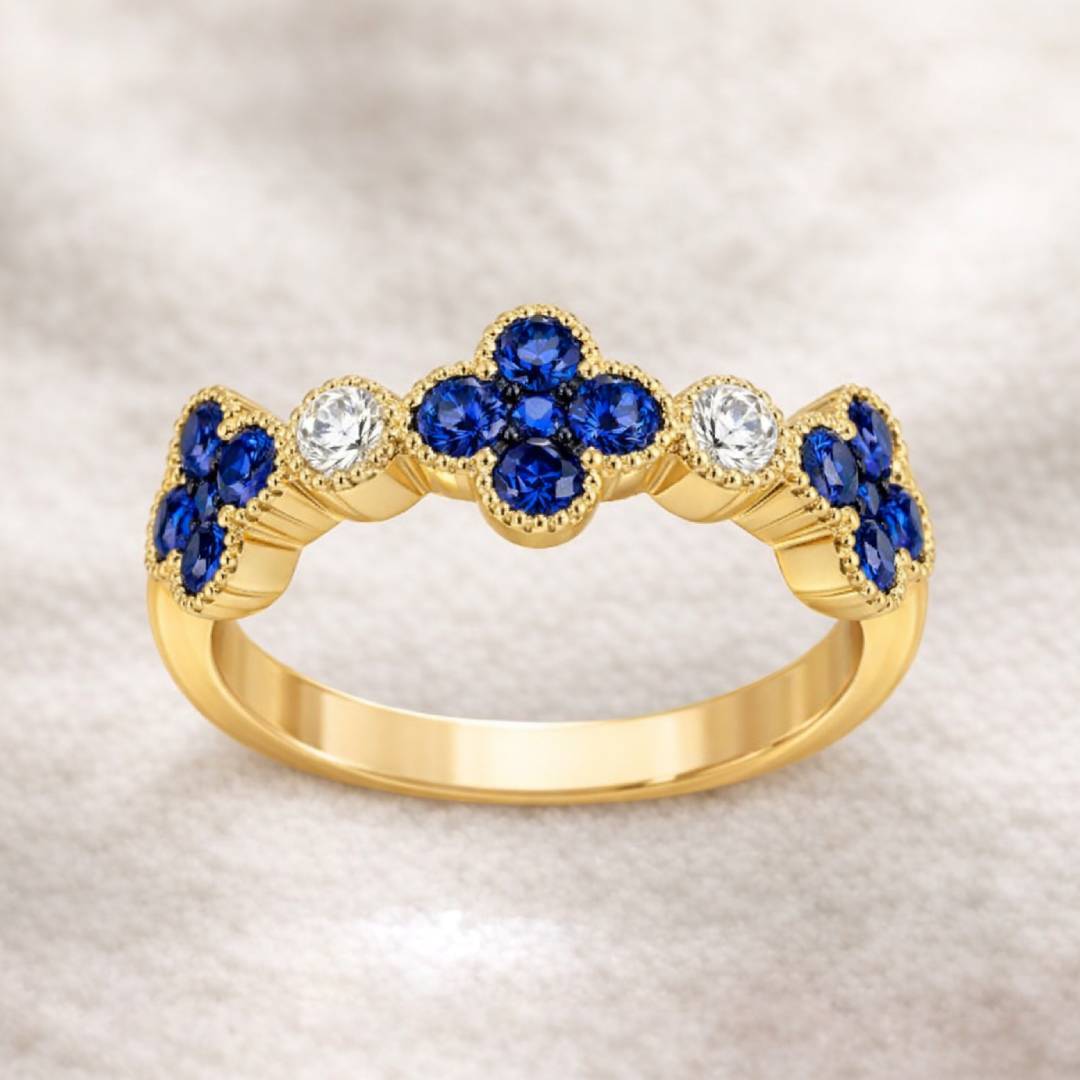 Gold ring with blue sapphire and clear gemstones on a beige background