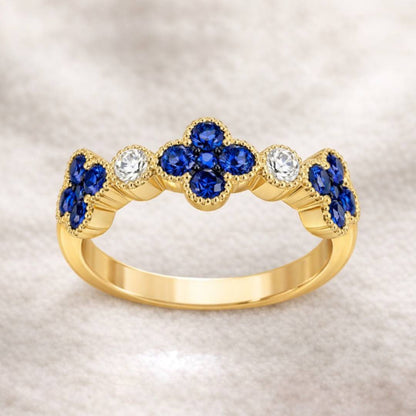 Gold ring with blue sapphire and clear gemstones on a beige background
