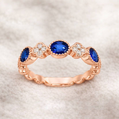 Rose gold ring with blue gemstones on a textured beige background