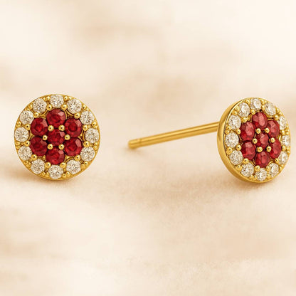 Gold earrings with red gemstones and clear stones on a beige background