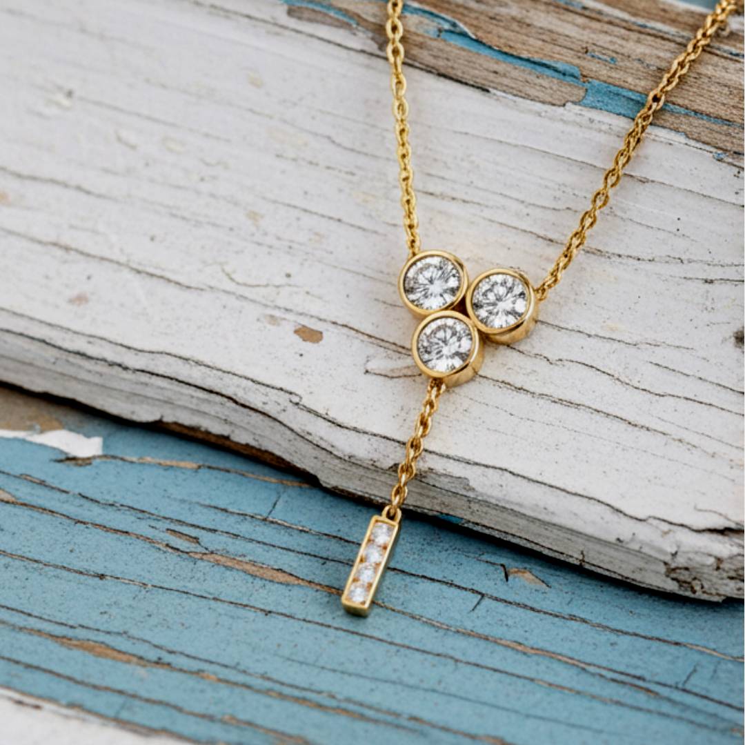 Gold necklace with three circular gemstones on a wooden surface