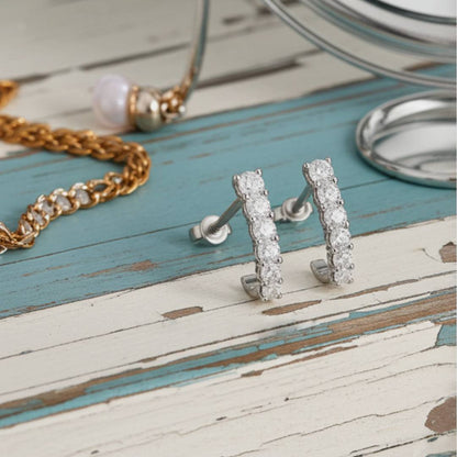 Pair of hoop earrings on a rustic wooden surface with a necklace in the background.