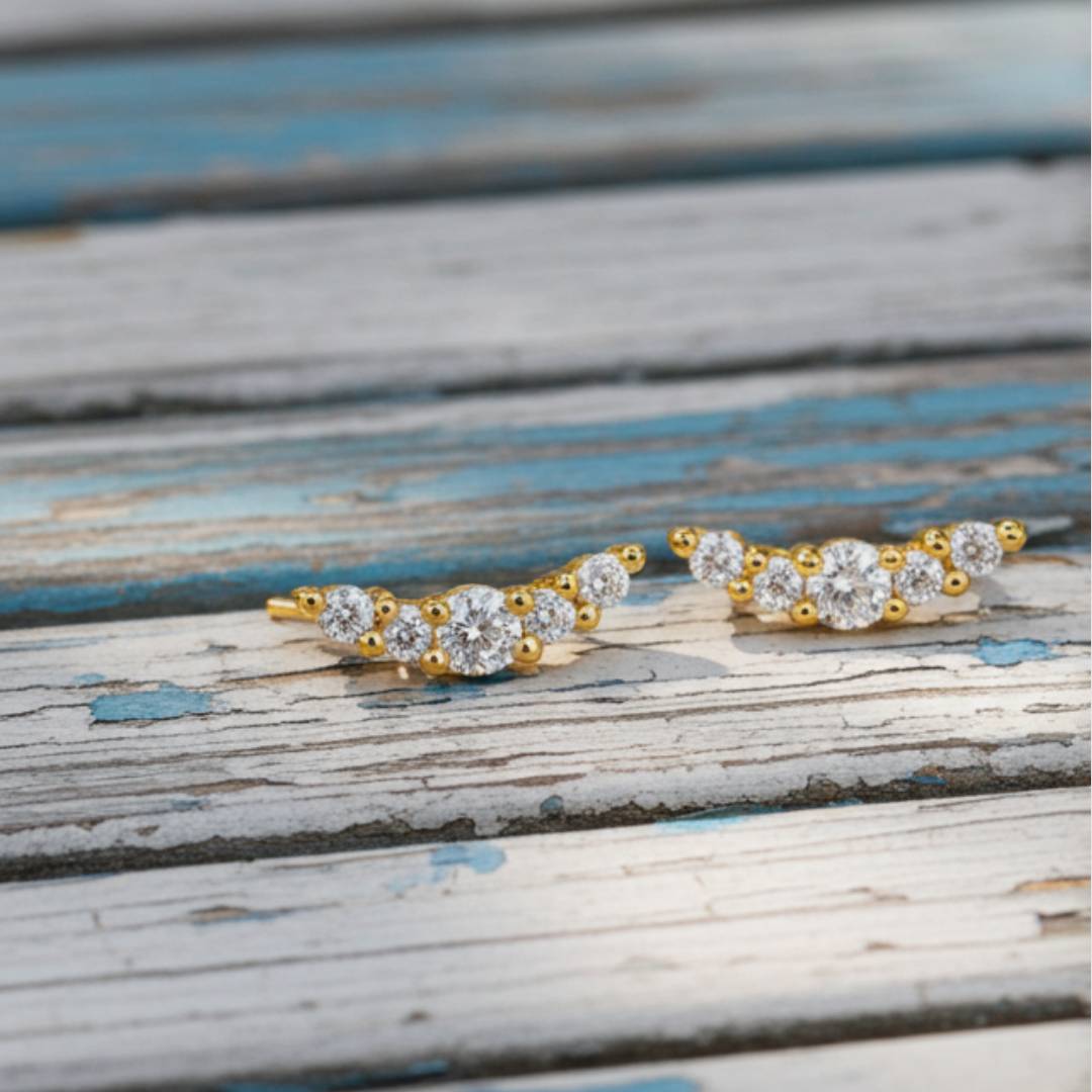 Pair of gold earrings on a wooden surface