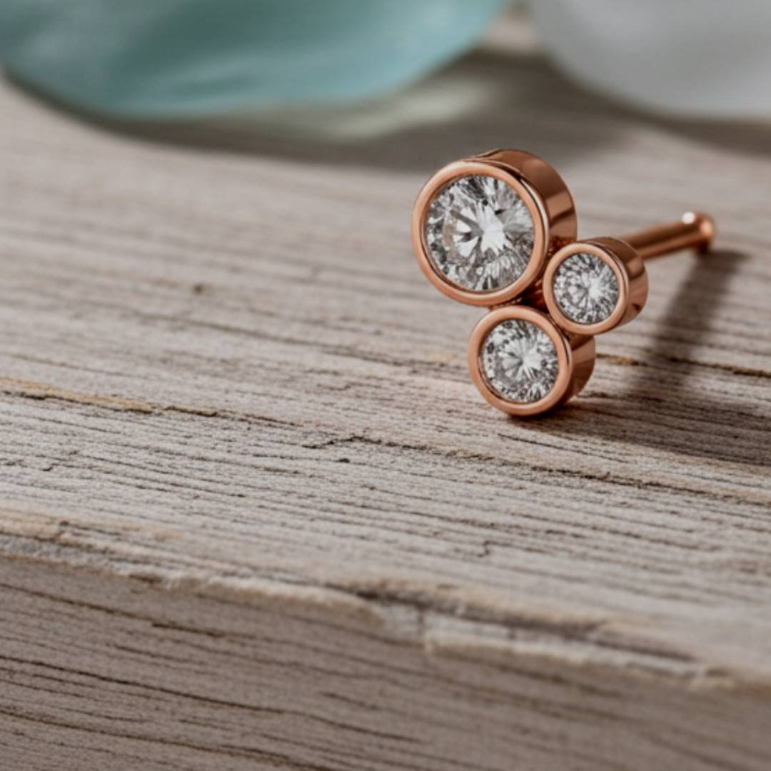 Rose gold earrings with clear gemstones on a wooden surface