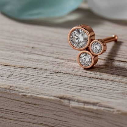 Rose gold earrings with clear gemstones on a wooden surface