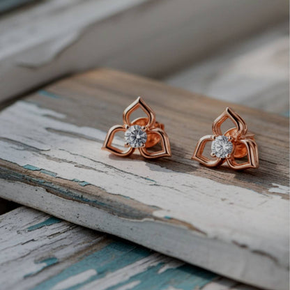Rose gold earrings with gemstones on a wooden surface