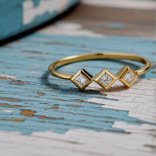 Gold ring with diamond-shaped stones on a textured blue surface