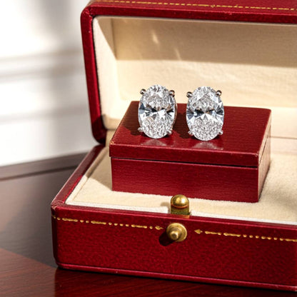 Diamond earrings in a red jewelry box on a wooden surface
