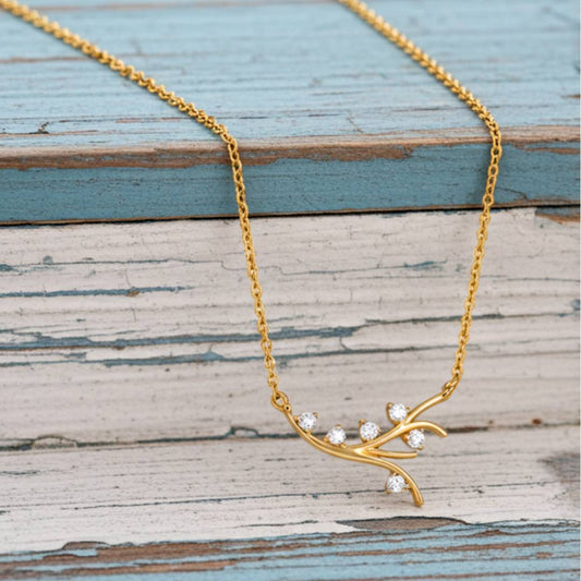Gold necklace with diamond-like stones on a wooden surface