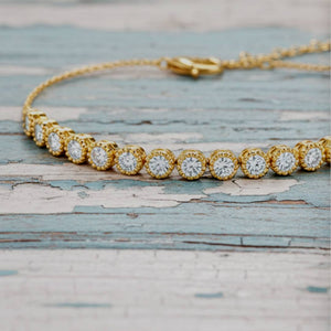 Gold bracelet with diamond accents on a textured wooden surface