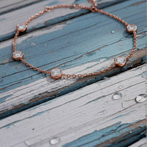 Rose gold bracelet with diamonds on a wooden surface