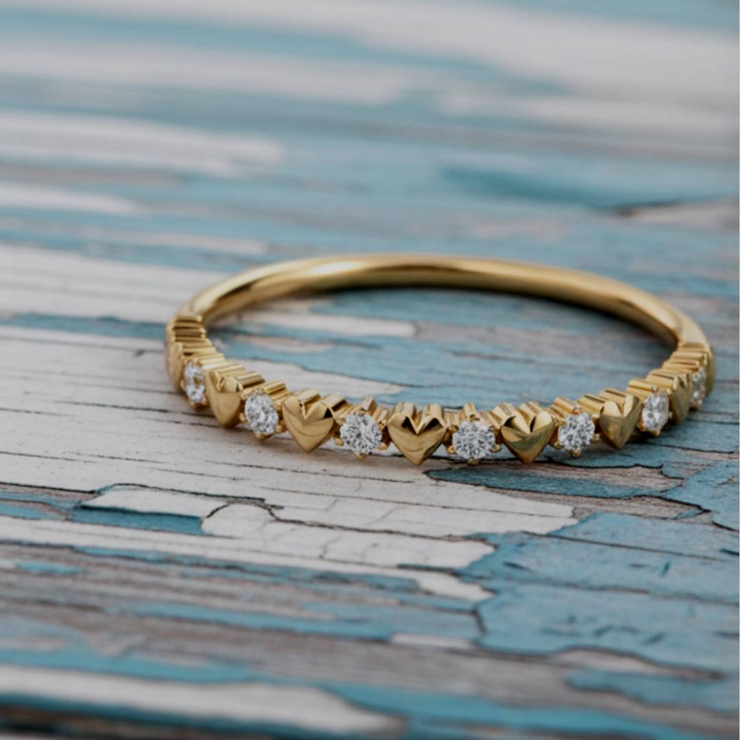 Gold ring with heart-shaped diamond accents on a textured surface