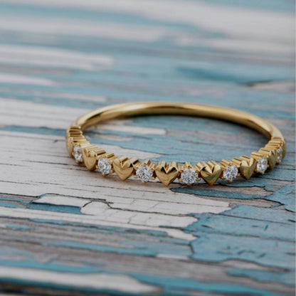 Gold ring with heart-shaped diamond accents on a textured surface