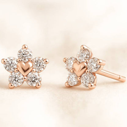 Rose gold earrings with heart design and clear gemstones on a beige background