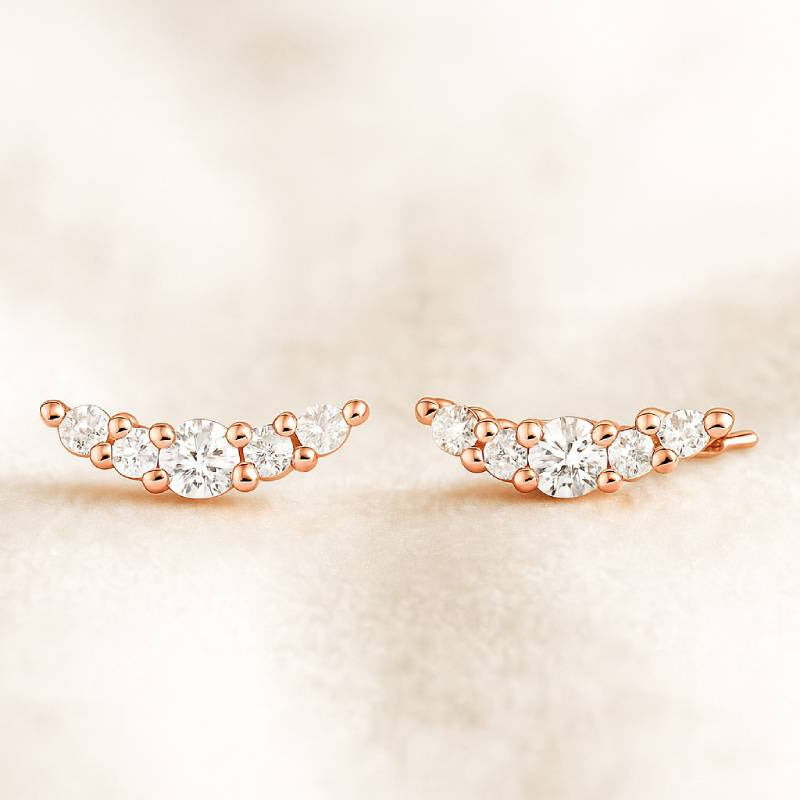 Rose gold earrings with clear gemstones on a beige background