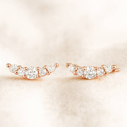 Rose gold earrings with clear gemstones on a beige background